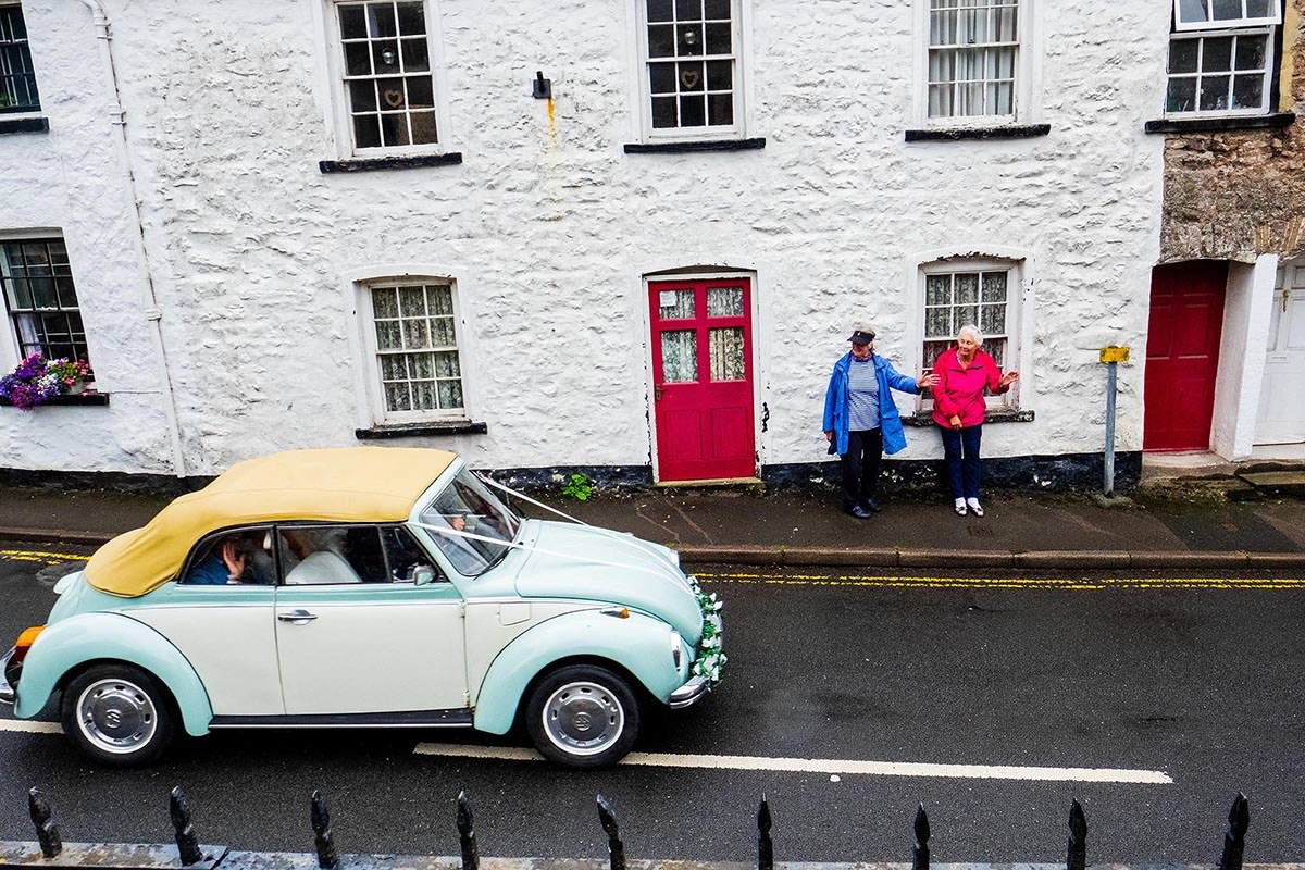 Local residents wave as bride and groom drive away following their Lake District wedding