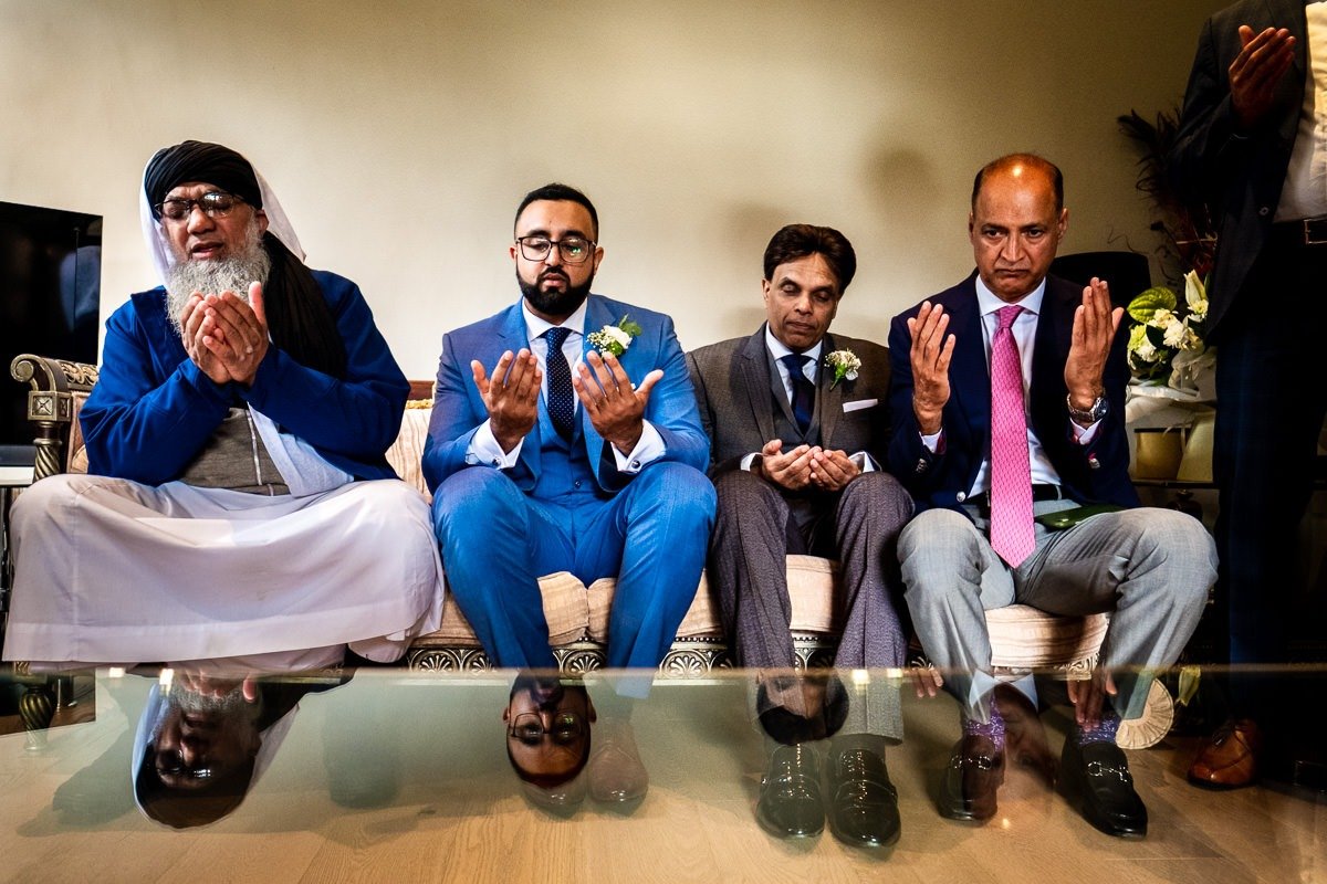 Groom and family pray during a reading at a Cheshire garden wedding