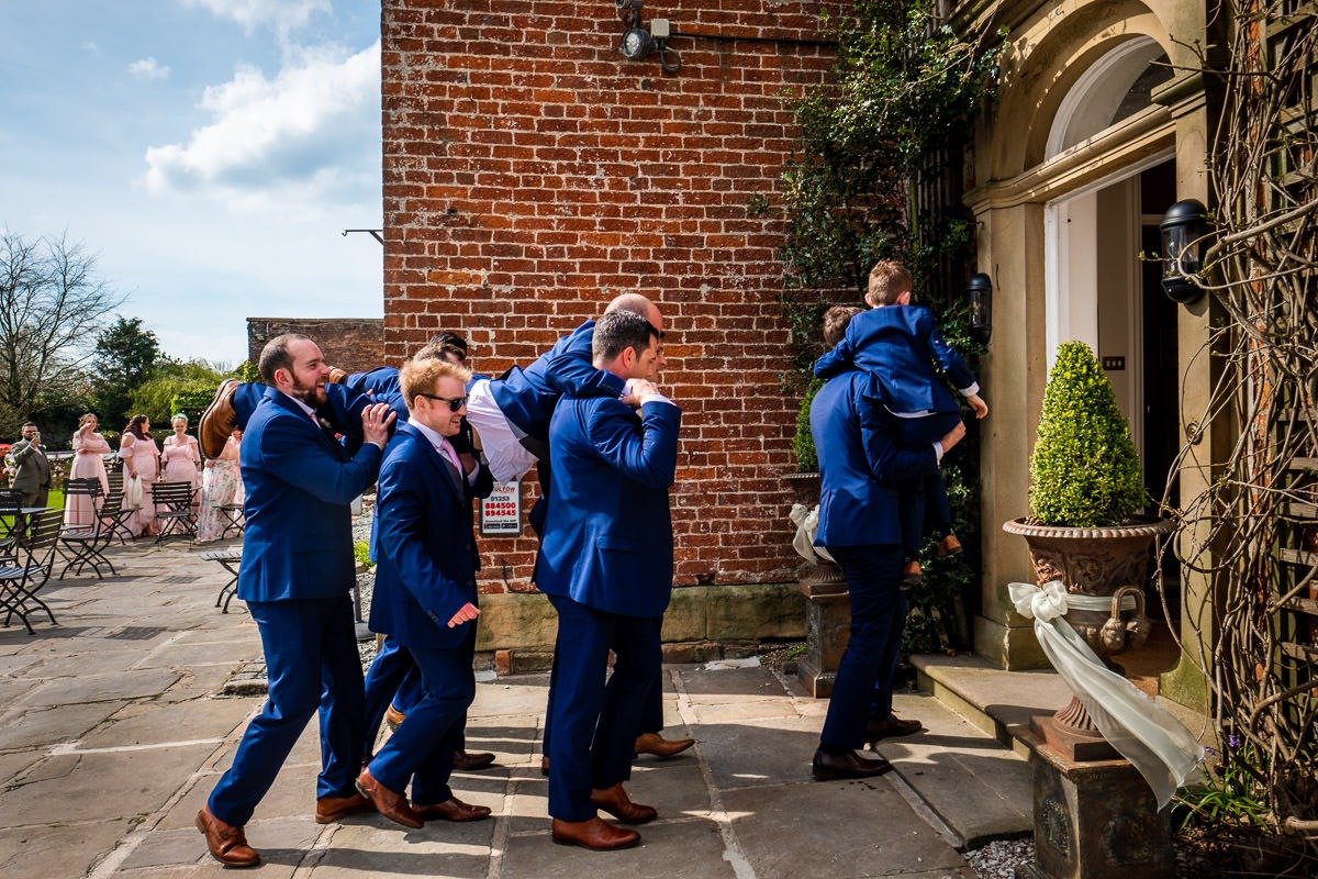 The best man is carried into the wedding breakfast at Singleton Lodge