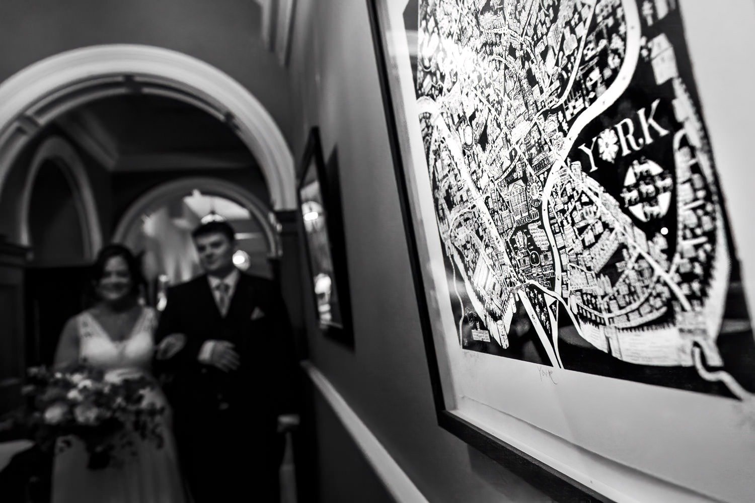 Bride and son walk down corridor in front of map of York at Grays Court wedding