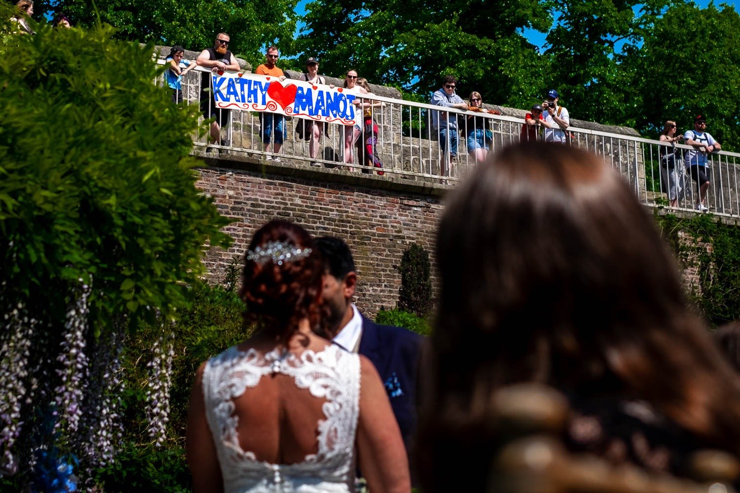 Friends display a banner for bride and groom from York walls above Grays Court garden