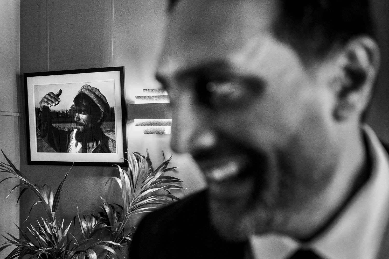 Groom smiles in front of old photo on wall