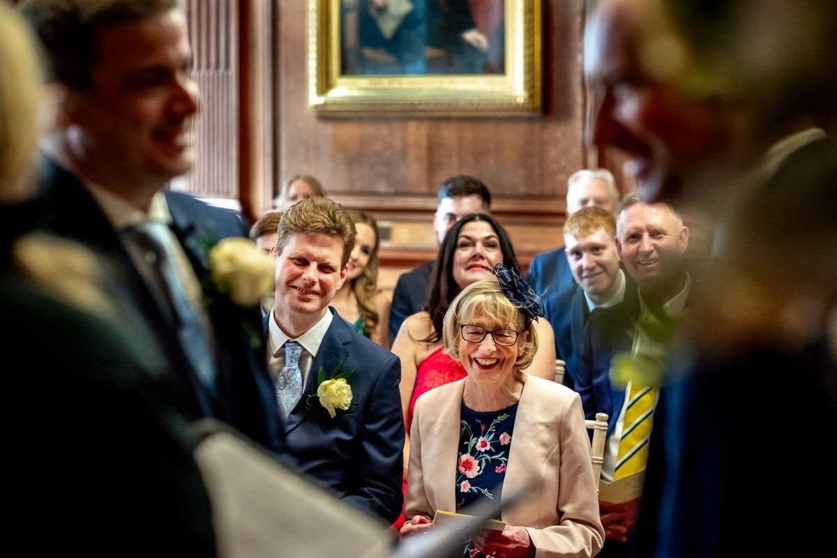 Mother and brother of groom smile during wedding ceremony