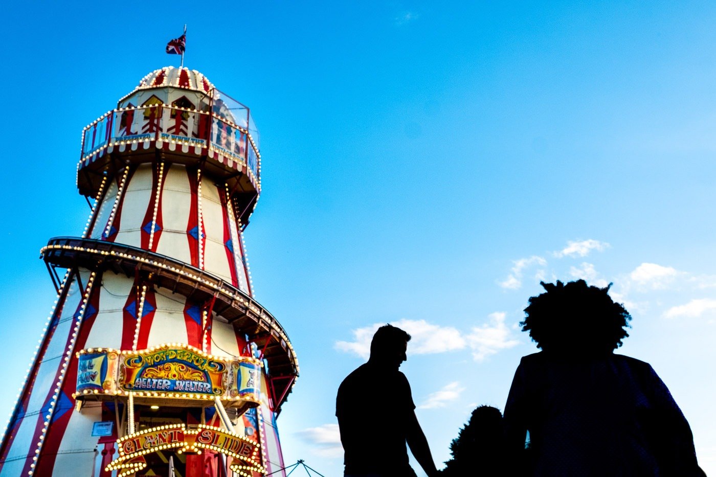 People silhouetted in front of a helter skelter at Camp Bestival