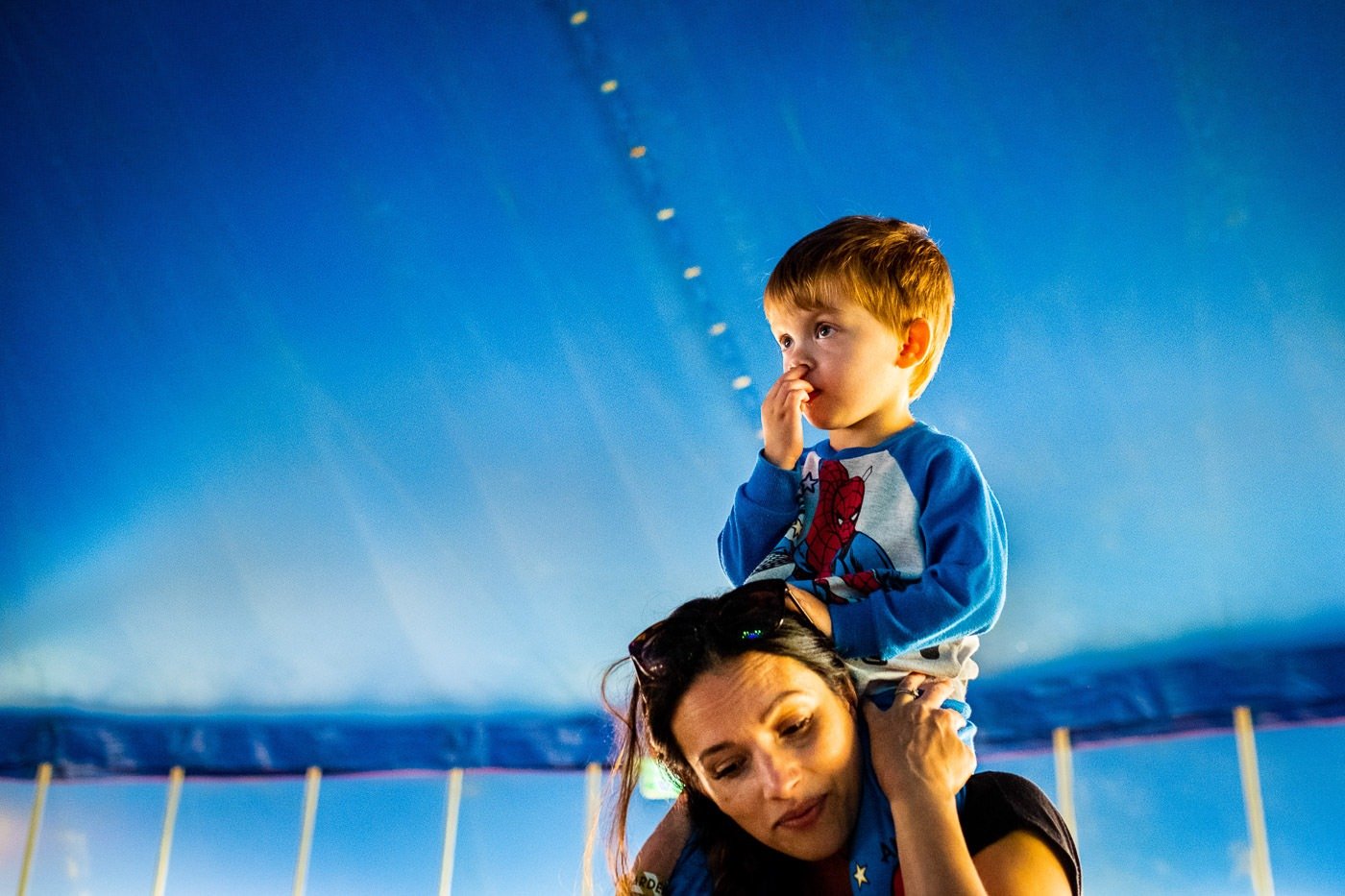 Child on mother's shoulders in a music tent at Camp Bestival