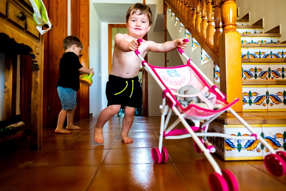 Child pushes kids' chair as another child plays with a toy