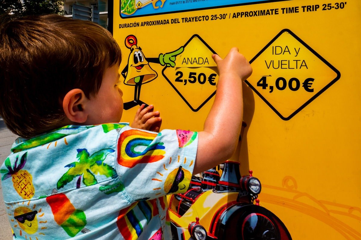 Child removes sticker from train poster in Sitges