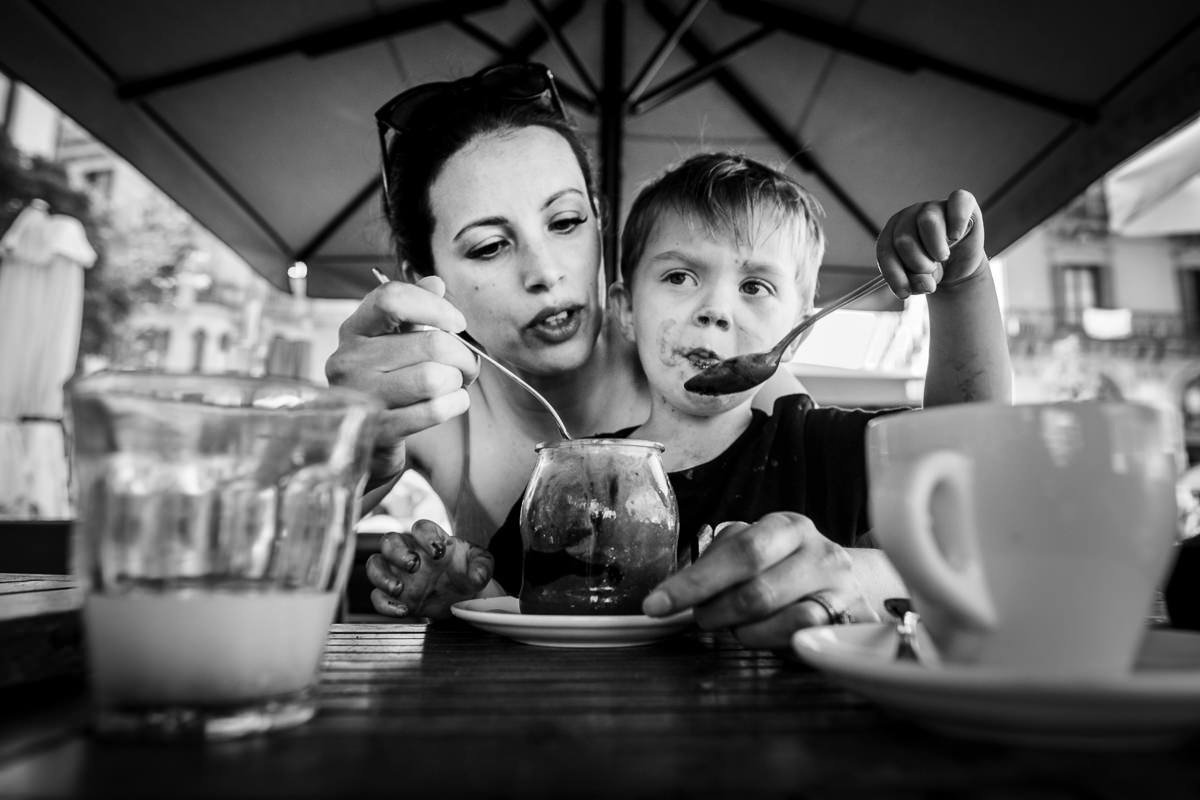 Mother and son eat chocolate dessert on family holiday in Barcelona