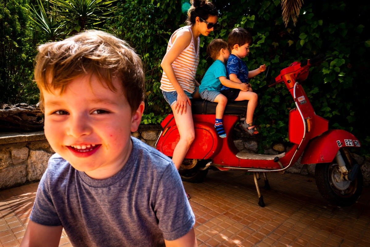 Children and adult sit on moped during family holiday in Vilanova i la Geltrú, Spain