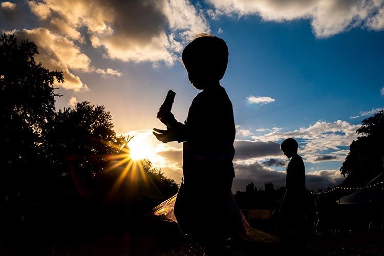 Silhouetted child eating ice cream as sun sets at Camp Bestival in Shropshire