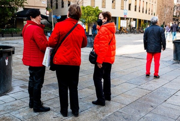 Three women wearing red coats next to a man wearing red trousers in Barcelona