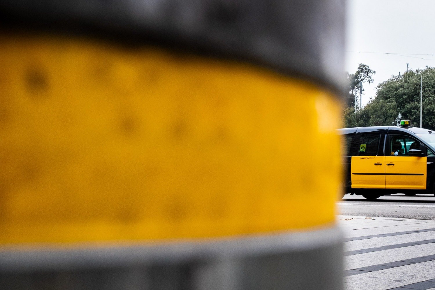 Yellow and black street post and yellow and black taxi