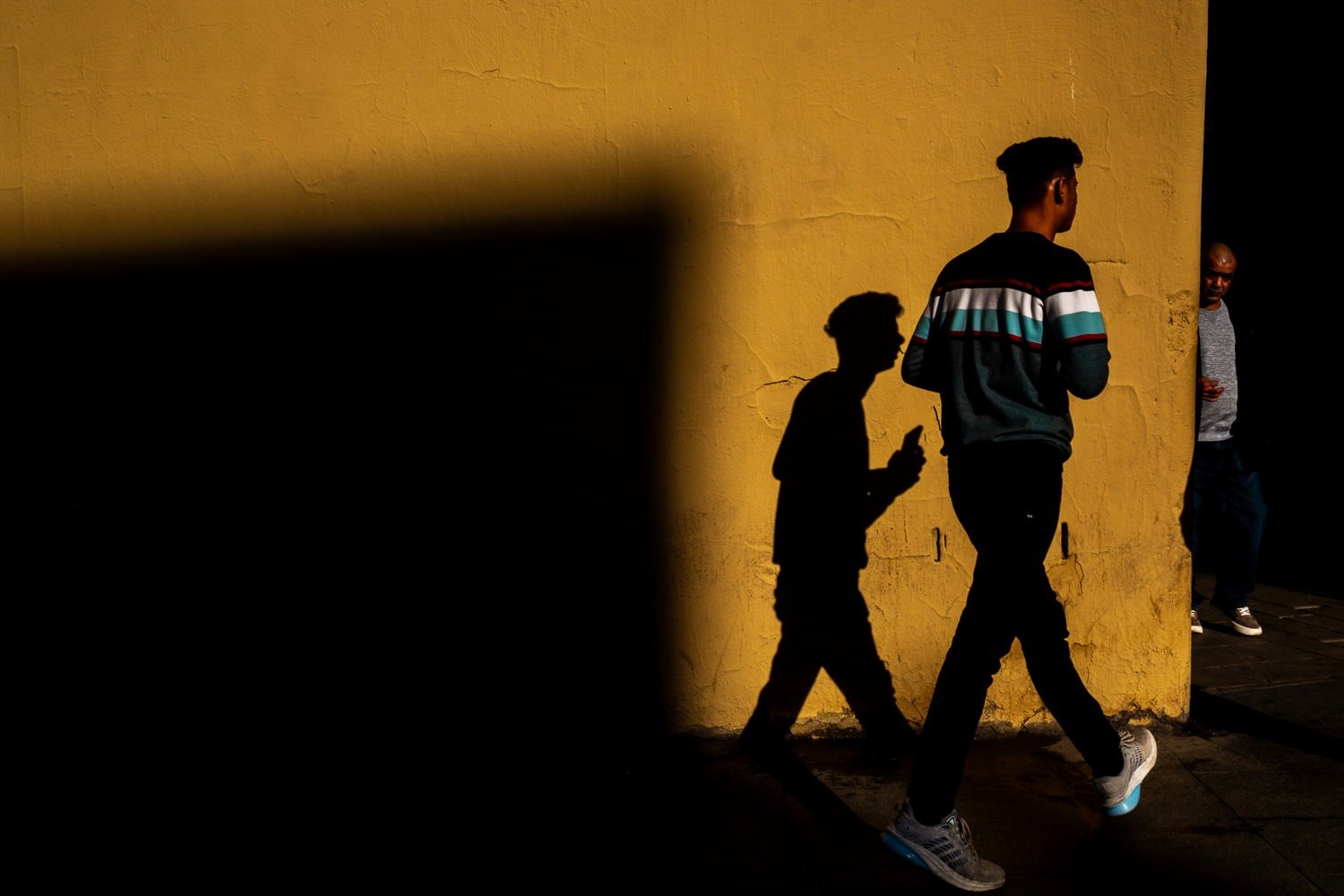 Man walks past yellow wall with silhouette