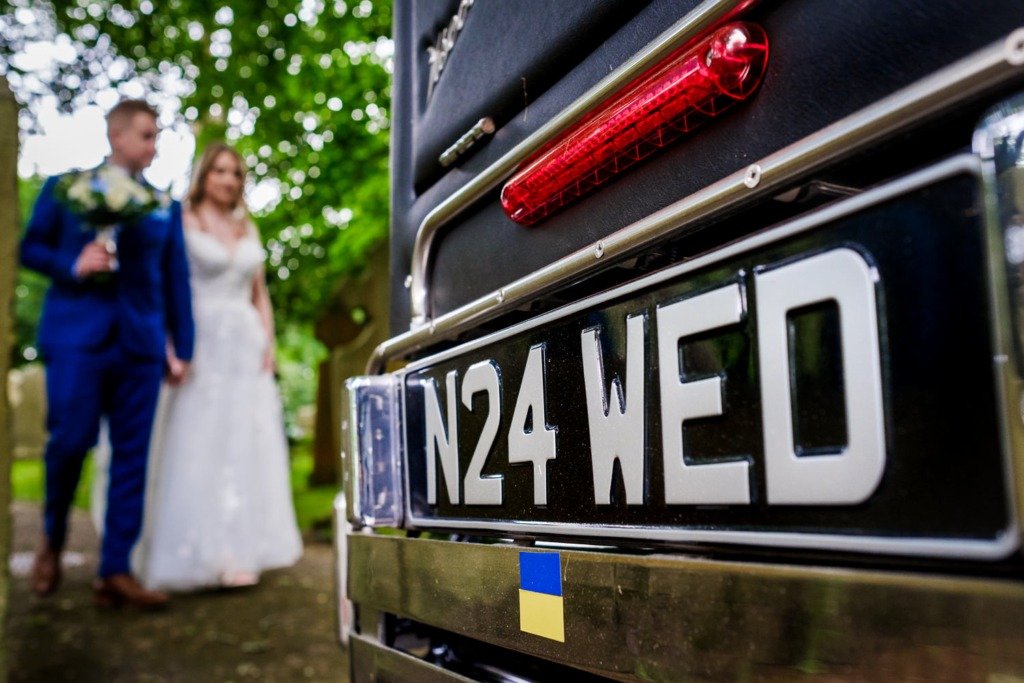 Bride and groom walk towards a wedding car with the number plater N24 WED, before travelling to celebrate their wedding at Mytton Fold Hotel