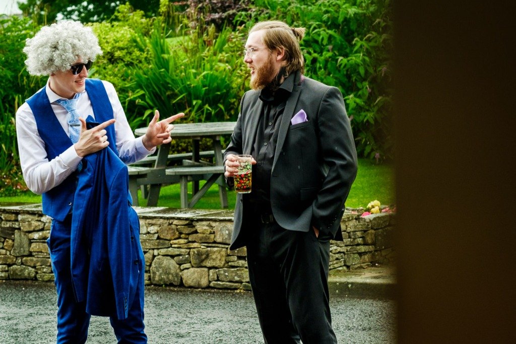 A guest wearing a wig gestures to another guest at a Mytton Fold wedding in the Ribble Valley, Lancashire