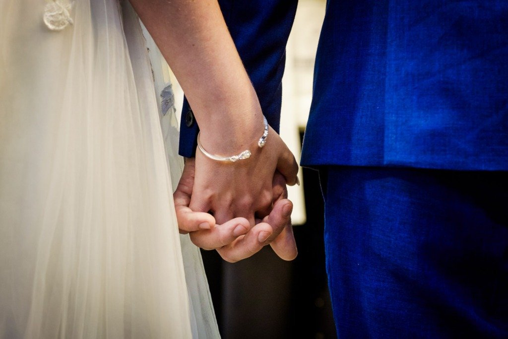 Close-up of the bride and groom holding hands after their marriage at Pleasington Priory, before celebrating at Mytton Fold Hotel in the Ribble Valley